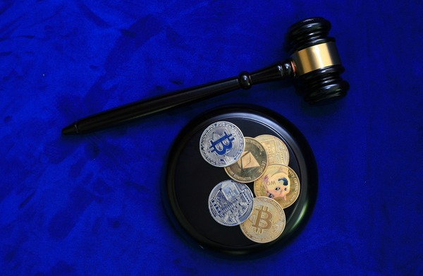 Judge gavel next to cryptocurrency coins on a blue background