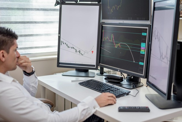Person working at a desk with several trading monitors