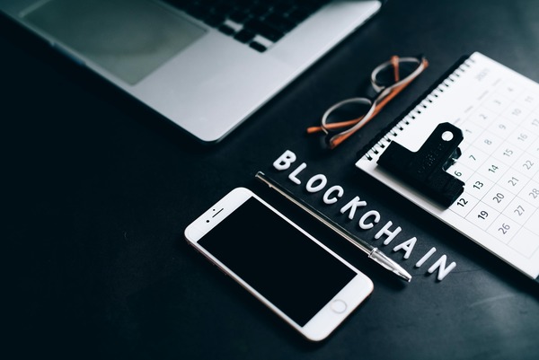 Smartphone with a blockchain app beside wooden letter tiles