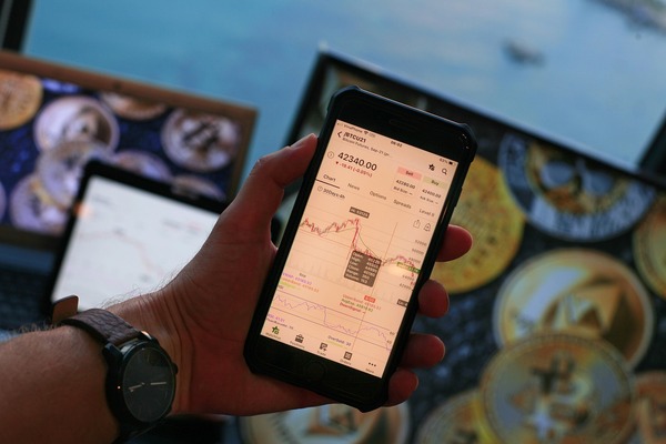 Hand holding a smartphone with a crypto trading chart