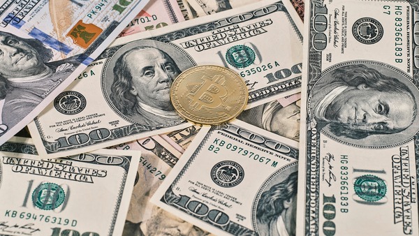 Gold crypto coin lying on US dollar banknotes