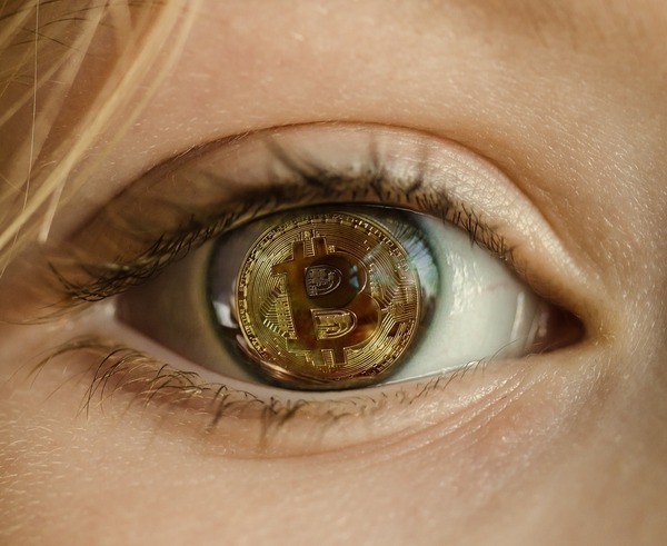 Close-up of an eye reflecting a golden Bitcoin coin